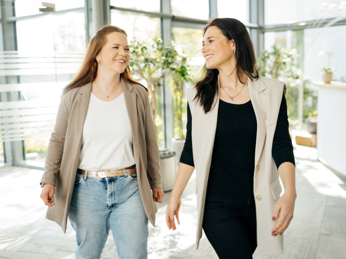 Zwei Frauen gehen in einem Bürogebäude entlang