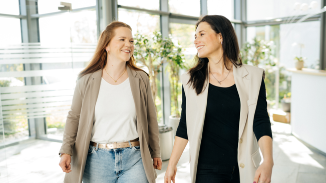 Zwei Frauen gehen in einem Bürogebäude entlang