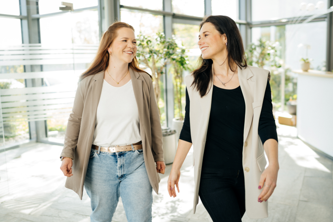 Zwei Frauen gehen in einem Bürogebäude entlang