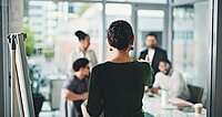 Führungskraft erklärt Team Aufgaben und Arbeitsanweisungen im modernen Büromeeting