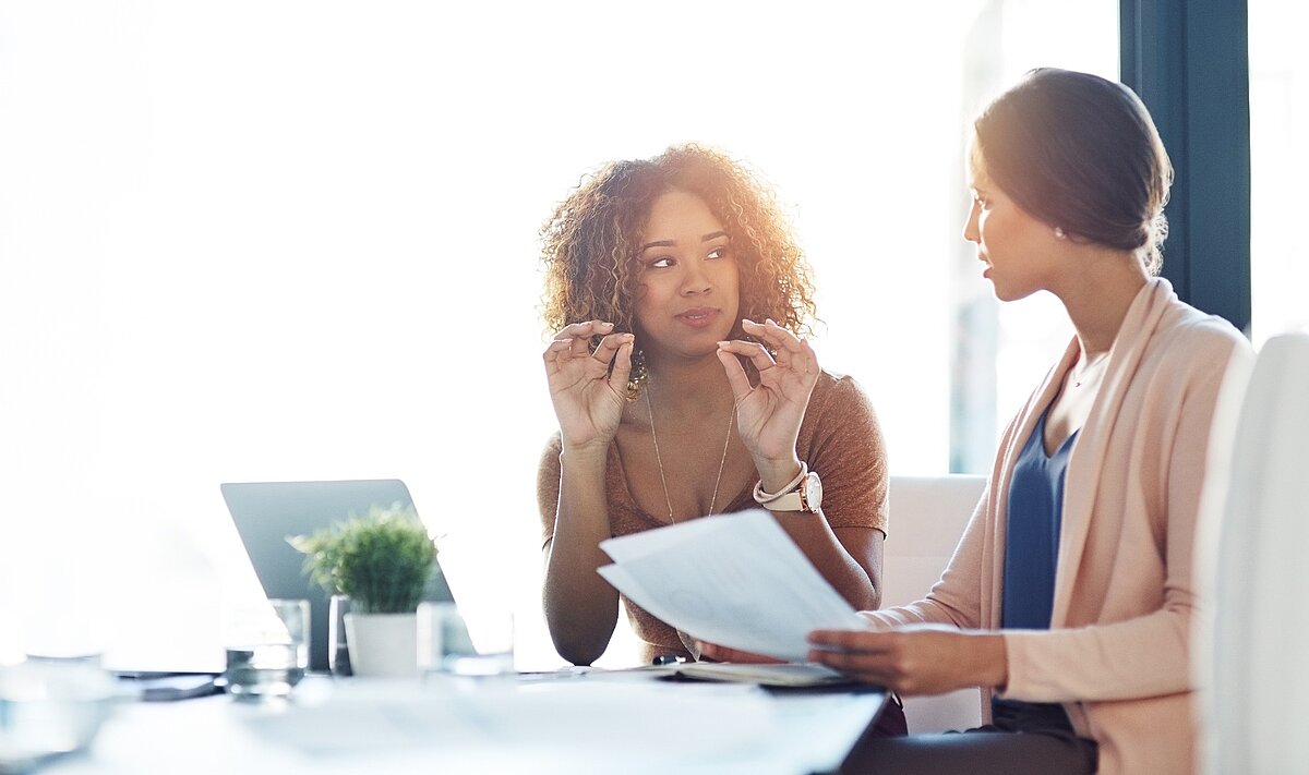 Zwei Frauen im Business-Meeting im Gespräch mit Unterlagen und Laptop
