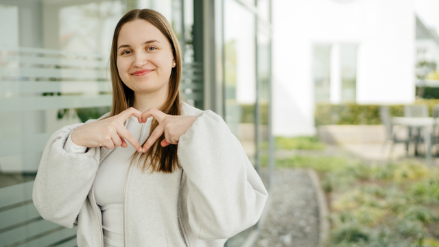 Junge Dame formt mit ihren Fingern ein Herz