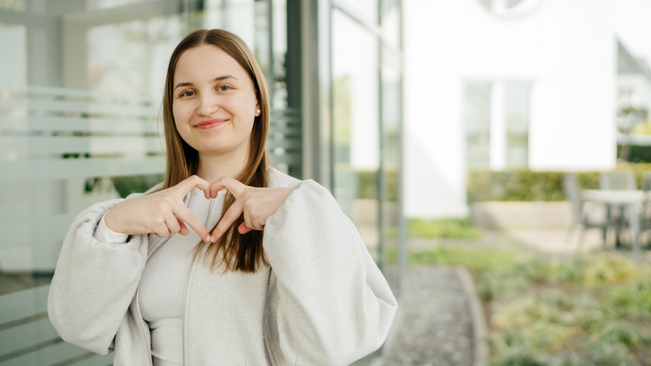 Junge Dame formt mit ihren Fingern ein Herz