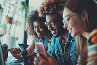 Drei Personen schauen auf ihr Handy und lächeln
