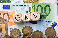 Würfel mit GKV Beschriftung liegen auf Geld