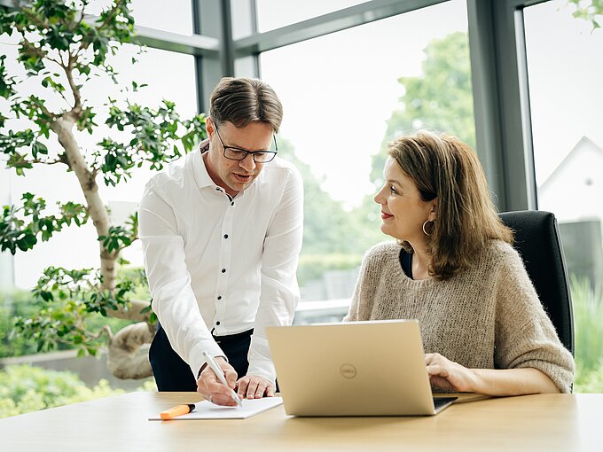 Zwei Arbeitskollegen am Schreibtisch diskutieren