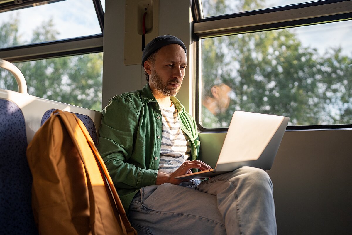 Mann arbeitet im Zug am Laptop