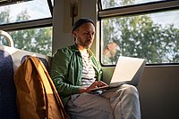 Mann arbeitet im Zug am Laptop