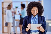 Frau lächelt mit einem Ipad in der Hand 