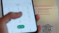 Person gibt eine Handynummer im Handy ein