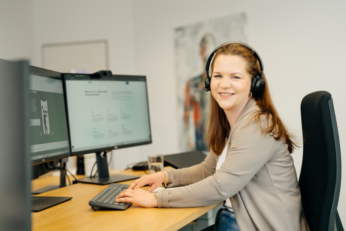 Frau arbeitet am Bildschirm und trägt ein Headset