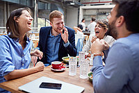 Vier Personen sitzen am Essenstisch und lachen