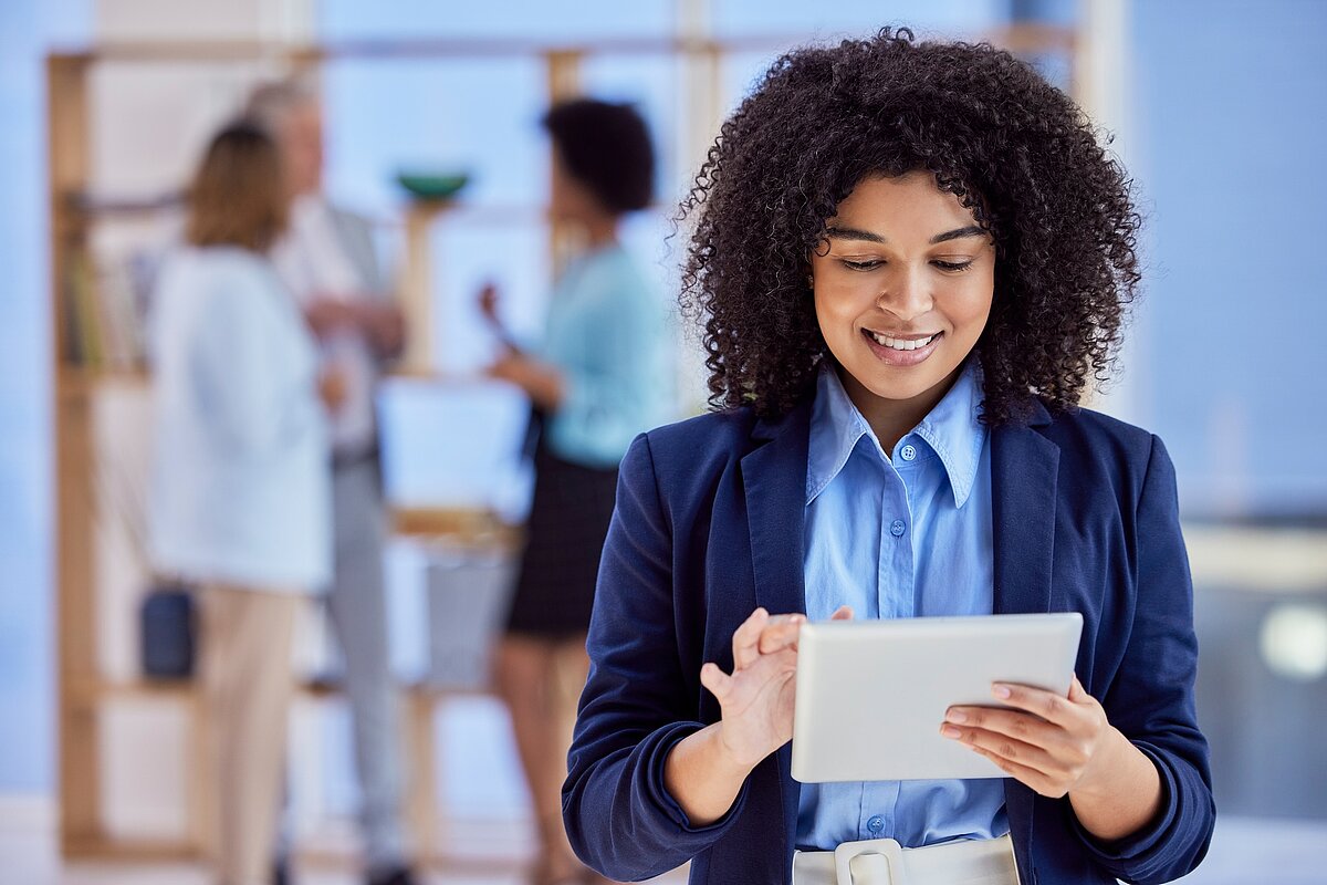 Frau lächelt mit einem Ipad in der Hand 