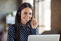 Mitarbeiterin einer Personalabteilung telefoniert vor einem Laptop mit Headset
