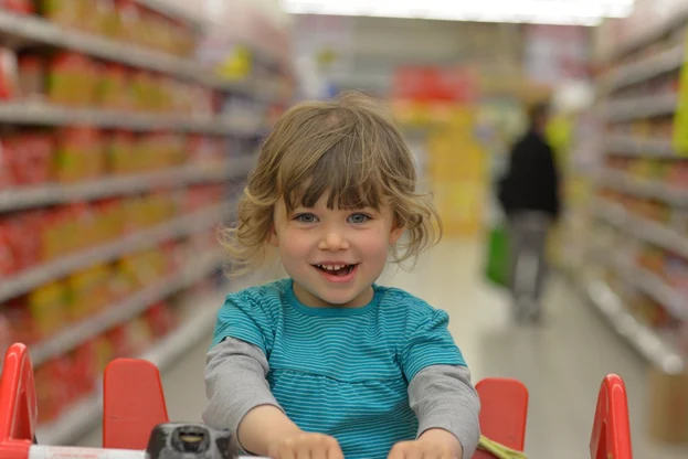 Kleines Kind sitzt im Einkaufswagen im Supermarkt