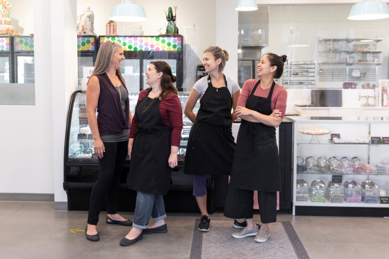 Vier Mitarbeiterinnen im Cafe stehen vor der Theke und lachen