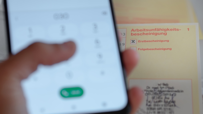Person gibt eine Handynummer im Handy ein