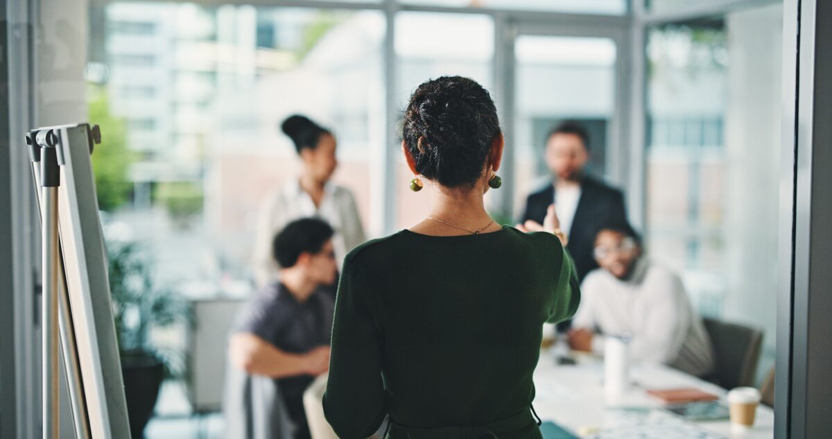 Führungskraft erklärt Team Aufgaben und Arbeitsanweisungen im modernen Büromeeting